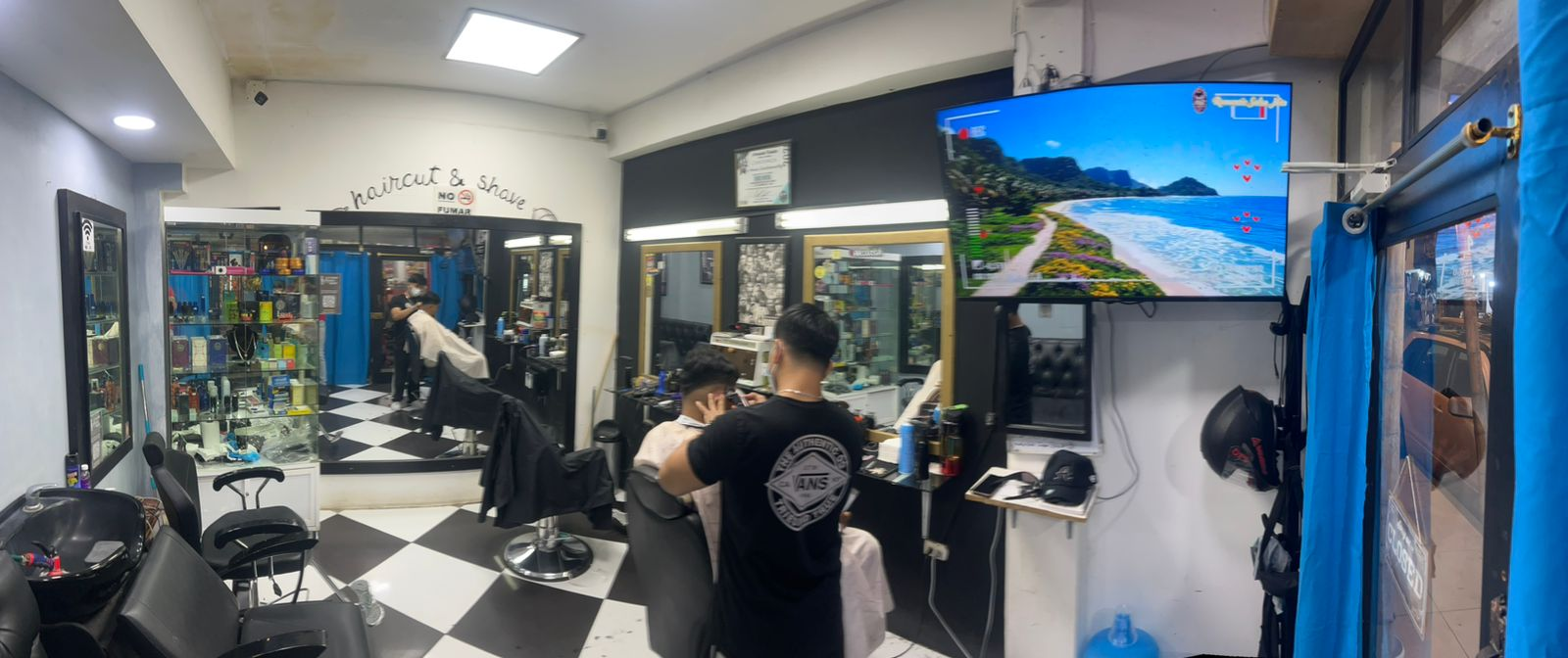 Interior de Nando Barber Shop con piso de damero y sillas de barbero